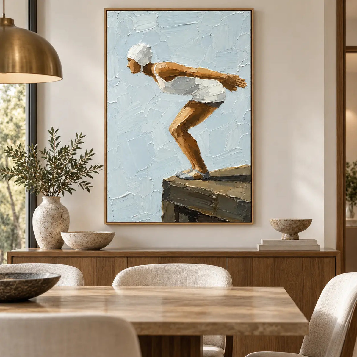 The Moment Before over a dining sideboard beneath a brass pendant and beside white candles
