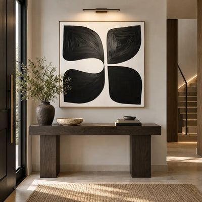 Four Forms Around a Pause: above a dark wood entrance console beneath a picture light beside illuminated stairs