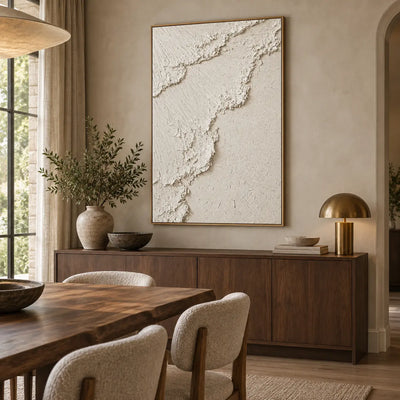The Ivory Ascent: above a dining sideboard with a brass dome lamp and leafy vase