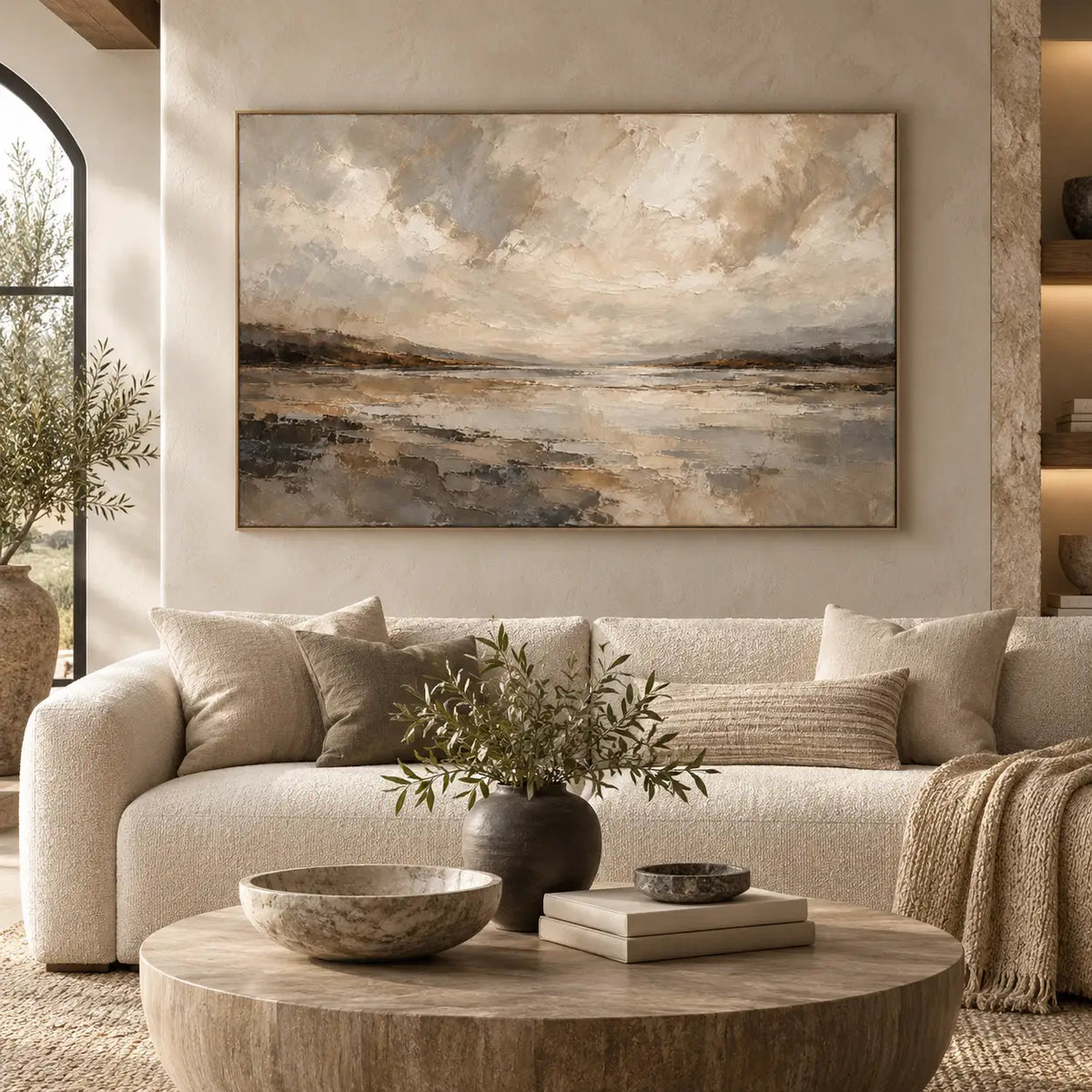 The Shore Beneath the Clouds above a curved ivory sofa near an arched window and wood coffee table