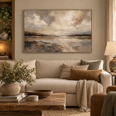 The Shore Beneath the Clouds above a sofa with warm beige cushions beside a curtained window