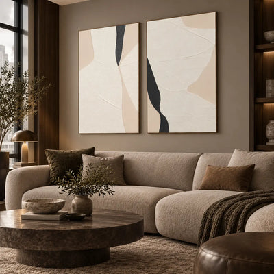 Two Openings in Cream: paired above a rounded cream sofa beside a city-view window