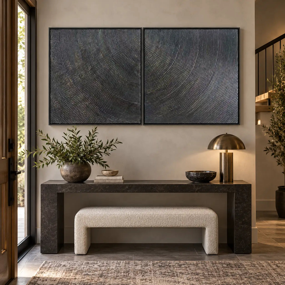 Two Rhythms in Charcoal: paired above a black stone entrance console with a cream bench and brass lamp